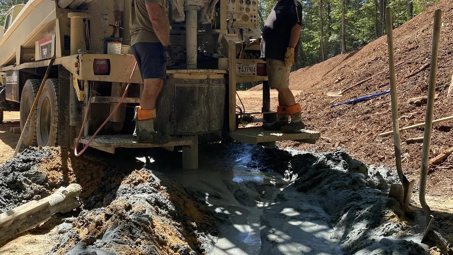 A drill rig boring a water well with drilling water running out across the site