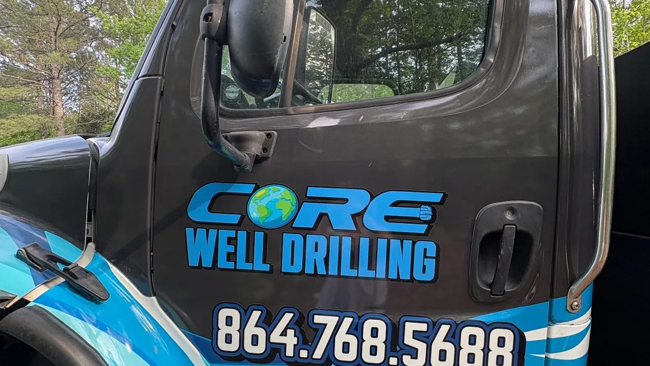 The Core Well Drilling logo and phone number on the door of the company's blue and black truck