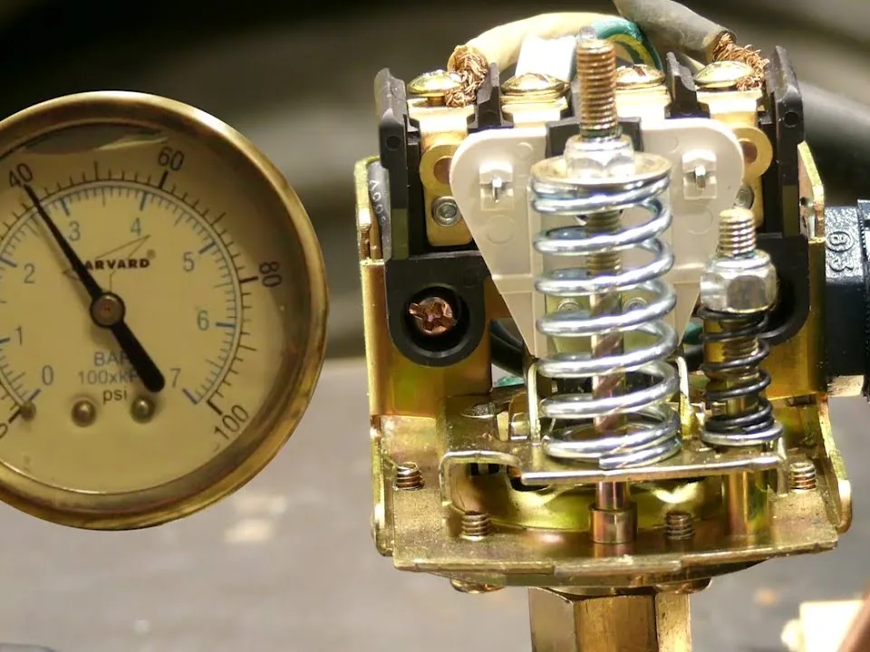 Close-up of a well pump pressure switch and pressure gauge reading about 40 psi on brass fittings
